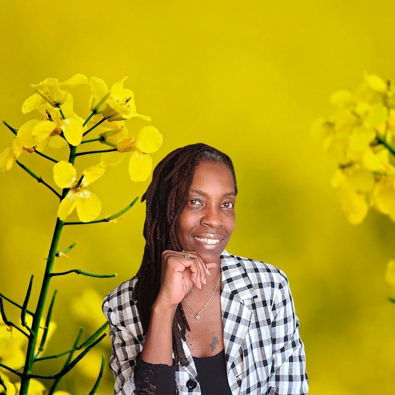 A woman standing in front of yellow flowers.