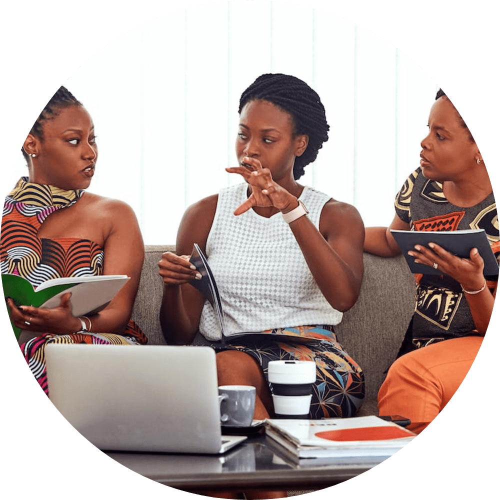 Three women sitting on a couch looking at their phones.