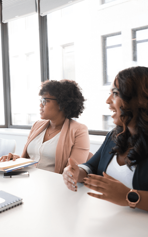 Two women sitting at a table talking to each other.