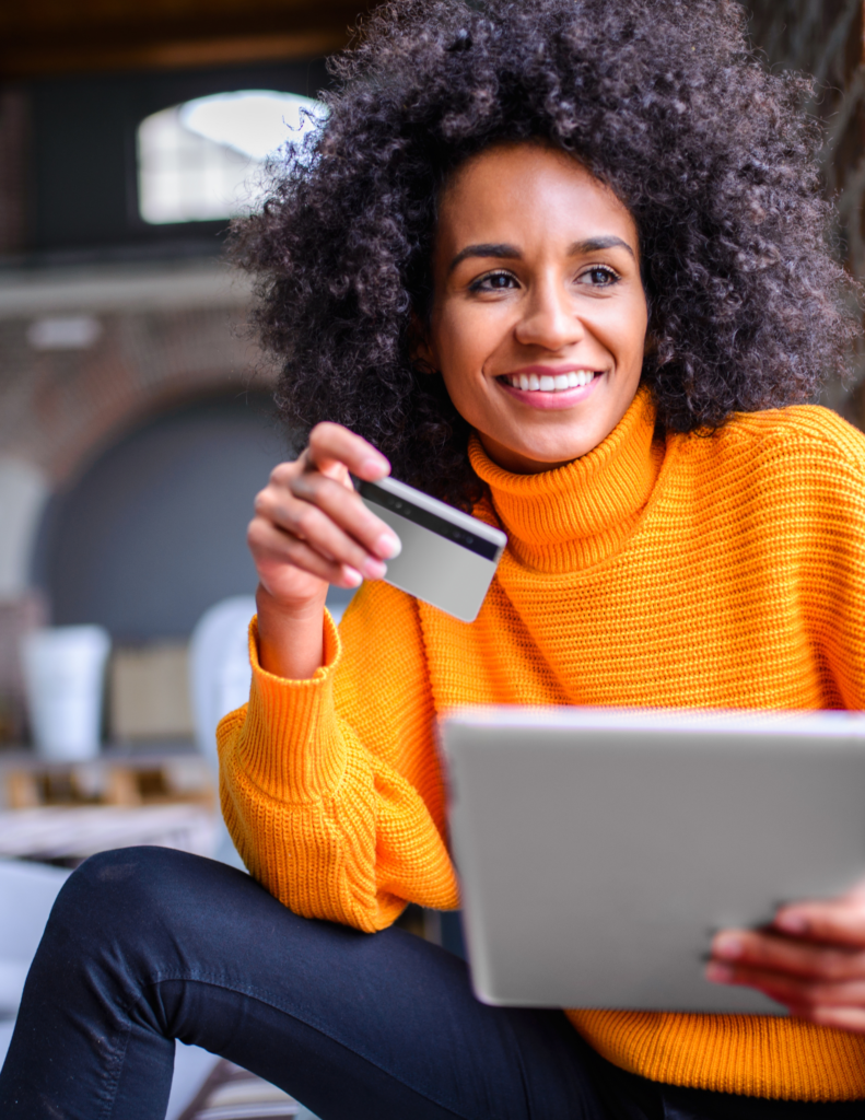A woman holding a credit card and using her laptop.