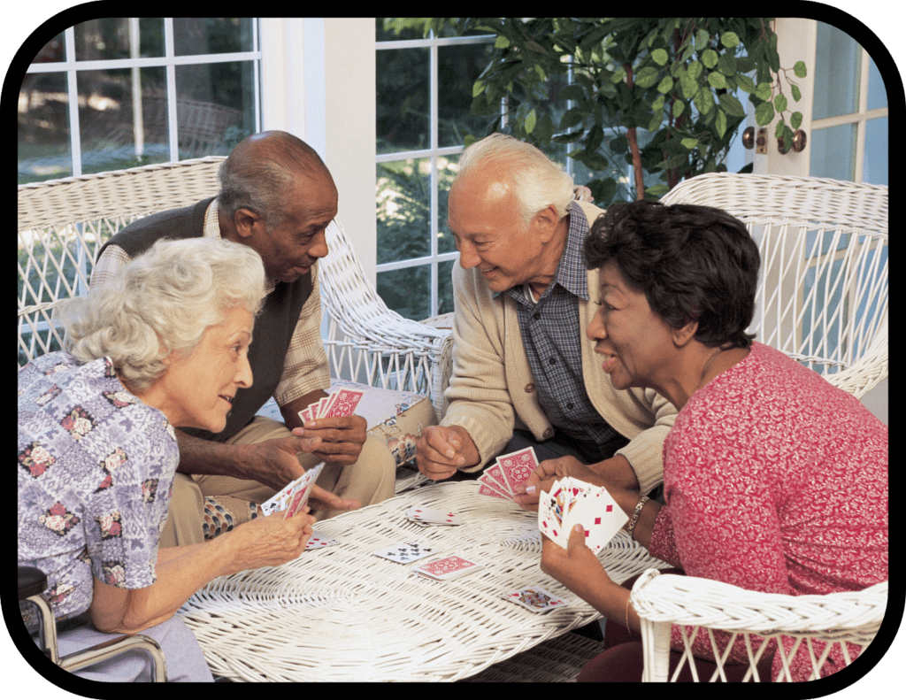 Four people playing cards on a porch.